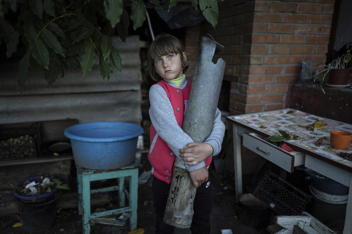 A 7-year-old girl holds a large piece of a rocket.
