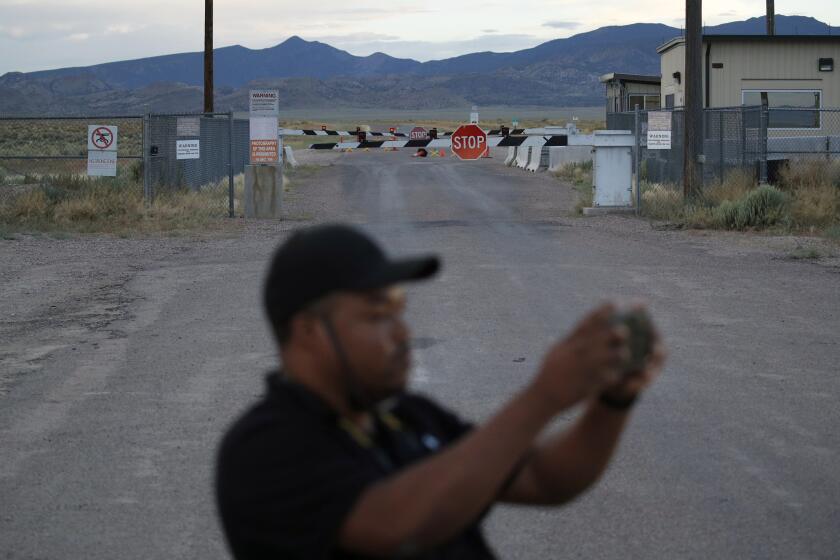 In this July 22, 2019 photo, Terris Williams visits an entrance to the Nevada Test and Training Range near Area 51 outside of Rachel, Nev. The U.S. Air Force has warned people against participating in an internet joke suggesting a large crowd of people "storm Area 51," the top-secret Cold War test site in the Nevada desert. (AP Photo/John Locher)