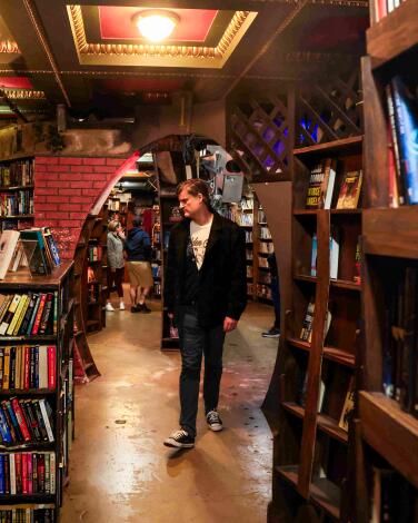 A person walks among shelves of books at a bookstore