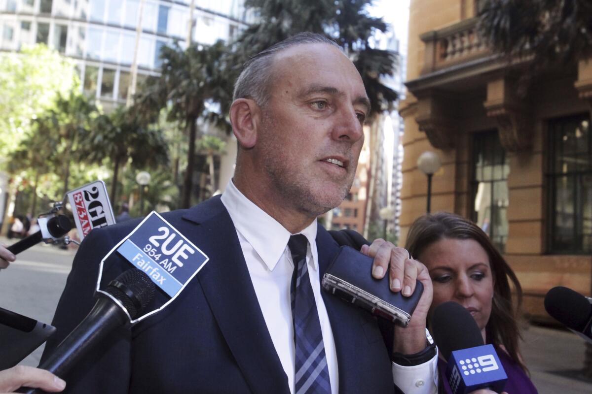 Brian Houston, founder of the Hillsong Church, surrounded by news microphones