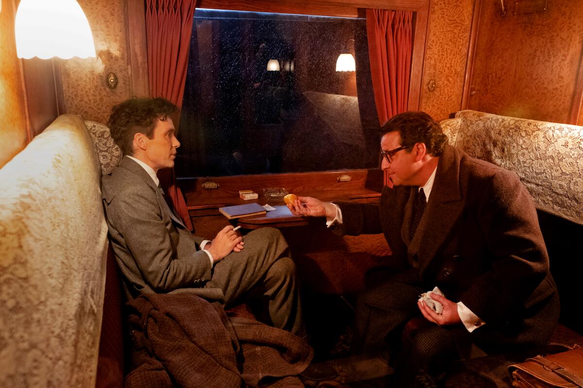 David Krumholtz leans over to Cillian Murphy and offers him something to eat. "Oppenheimer." 
