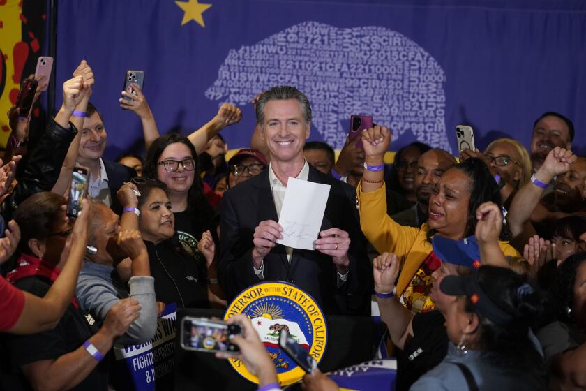California Gov. Gavin Newsom signs the fast food bill surrounded by fast food workers at the SEIU Local 721 in Los Angeles, on Thursday, Sept. 28, 2023. Anneisha Williams, right, who works at a Jack in the Box restaurant in Southern California celebrates as she holds up the bill. (AP Photo/Damian Dovarganes)