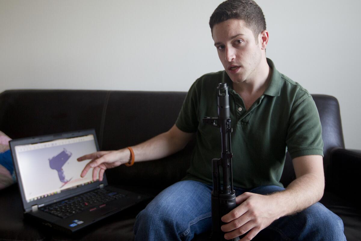 Texas resident Cody Wilson points to to his laptop screen, where an image of a prototype plastic gun is displayed, in 2012. In his other hand he holds a weapon he calls "Individual Mandate."