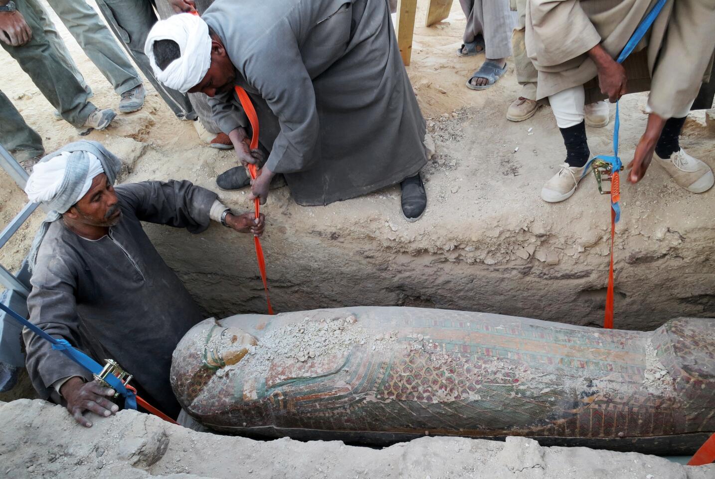 Workers lift a 3,600-year-old wooden sarcophagus from the ground in the ancient city of Luxor, Egypt.