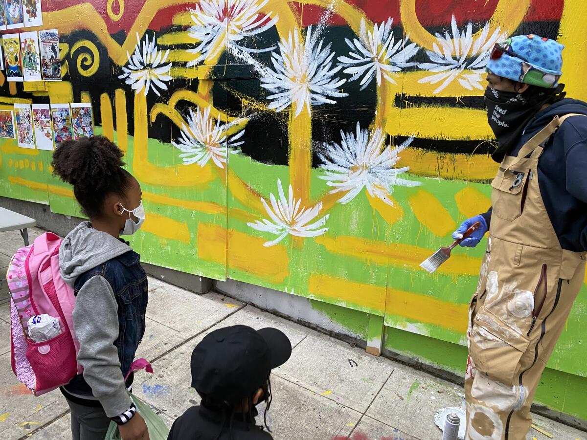 Malcolm Procter talks with children viewing his mural on plywood in Seattle's "autonomous zone."