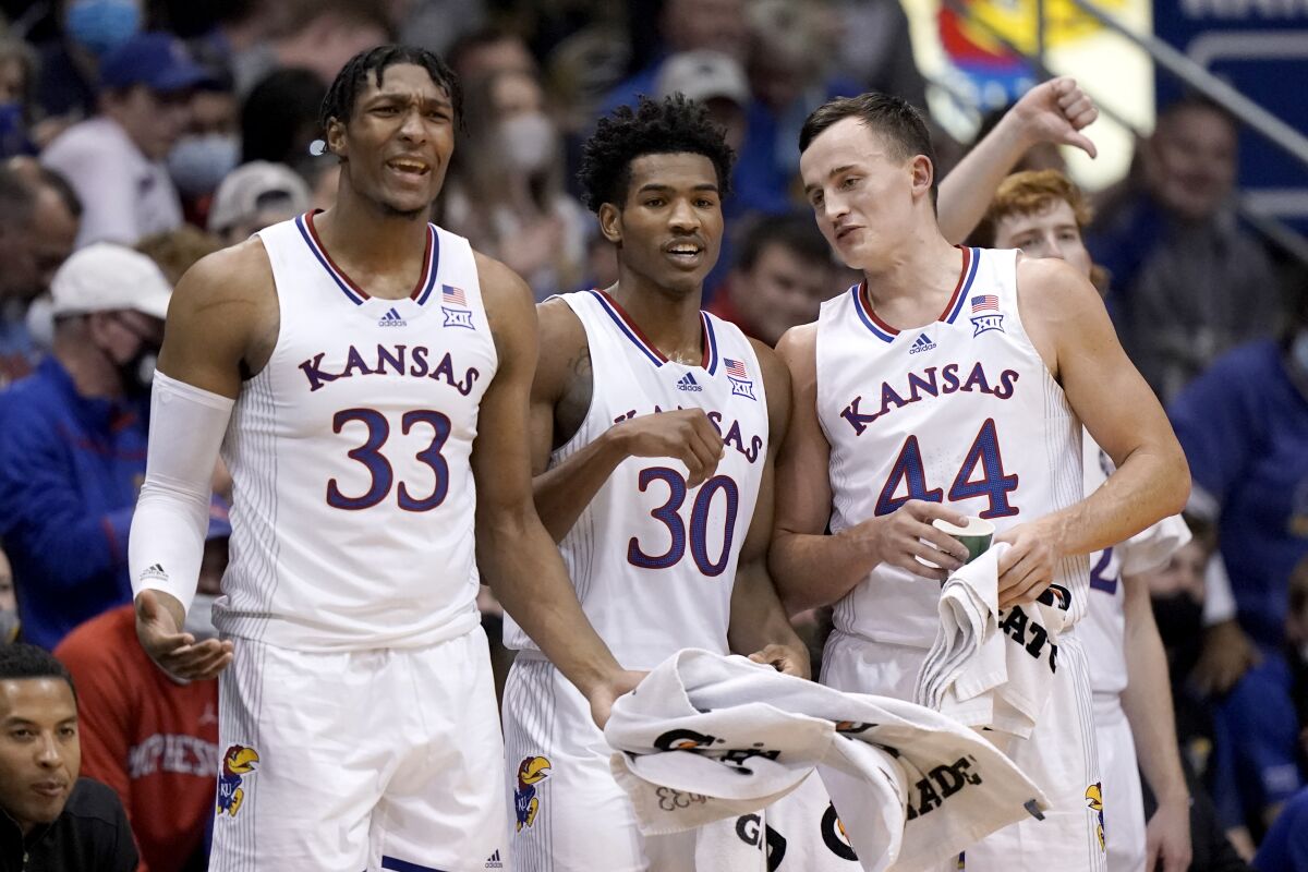 Kansas' David McCormack (33), Ochai Agbaji (30) and Mitch Lightfoot (44) watch from the bench during the second half of an exhibition NCAA college basketball game against Emporia State Wednesday, Nov. 3, 2021, in Lawrence, Kan. (AP Photo/Charlie Riedel)