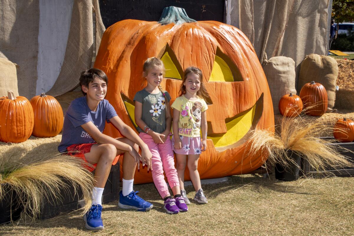 Rafael, Veronica and Amelia Barraza pose in front of a giant pumpkin at Costa Mesa's Scarecrow Festival in 2022.