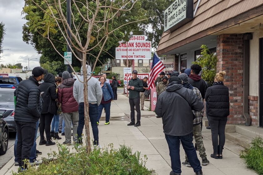 An employee of Burbank Ammo & Guns talks to customers who were looking to purchase a firearm and ammunition in light of the coronavirus pandemic, on Monday March 16, 2020.