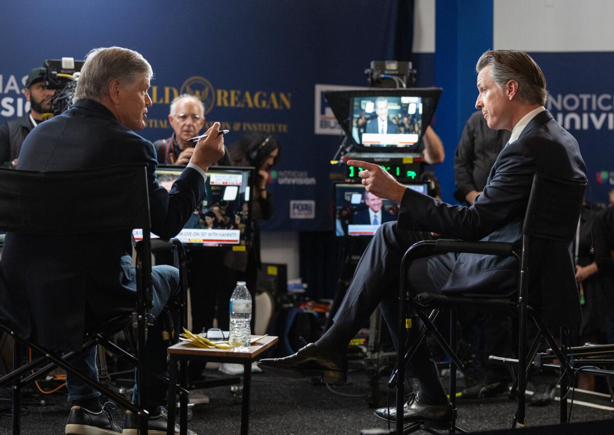 Behind-the-scenes view of Sean Hannity and Gavin Newsom speaking in front of cameras