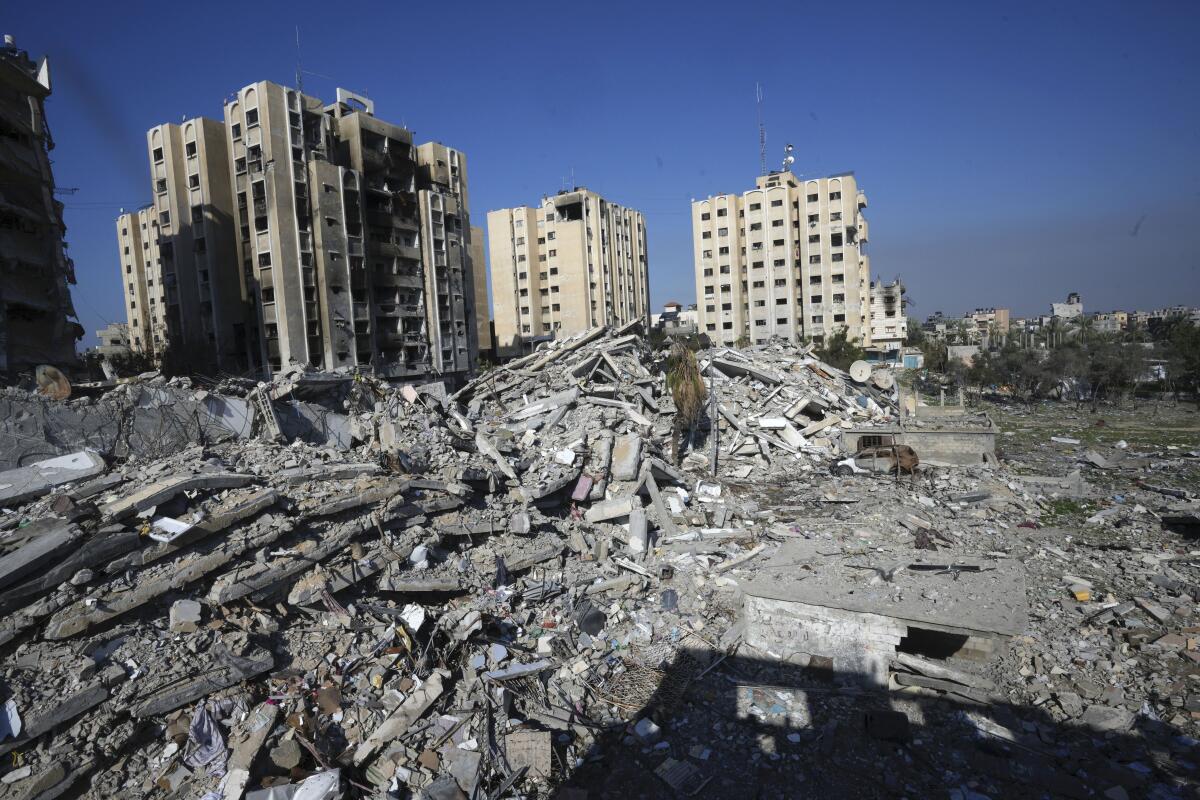 Damaged buildings serve as the backdrop to the rubble of demolished buildings 