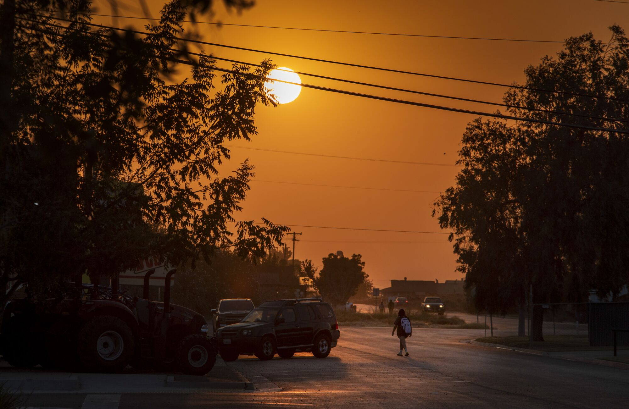 A high schooler walks towards a bus stop as the sun rises above Main Street in Stratford.