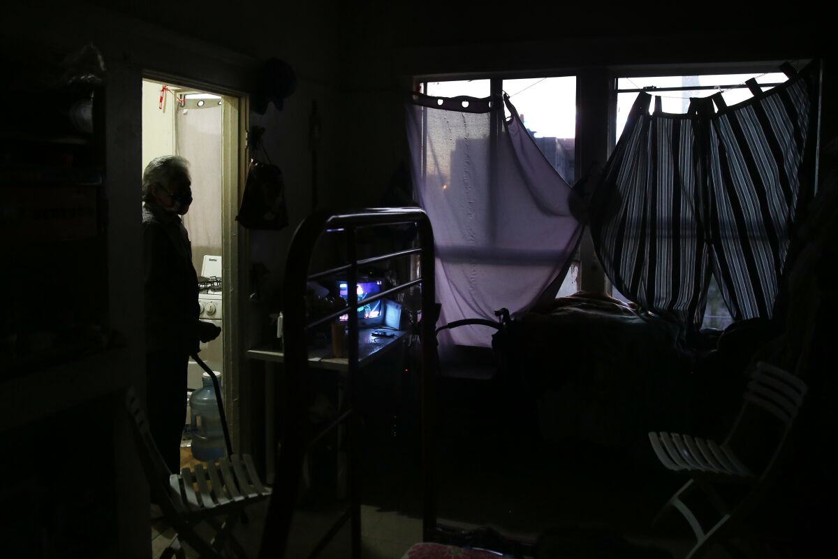 Light shines through the windows of a modest apartment with makeshift curtains.