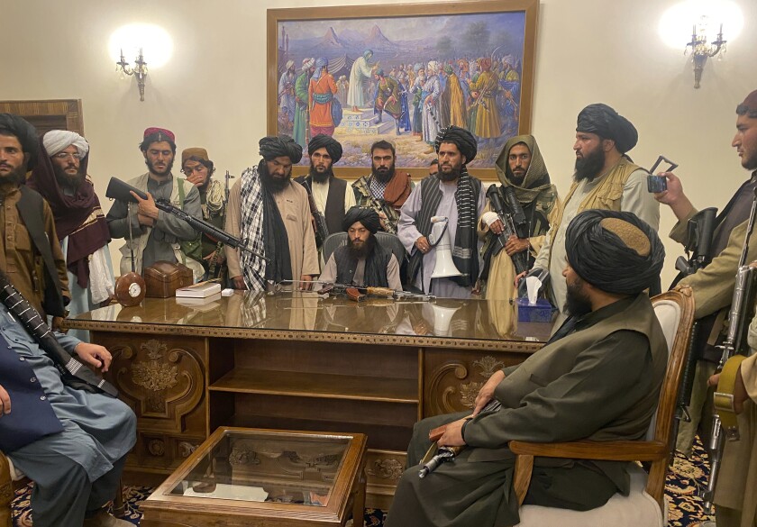 Taliban behind a desk in the Afghan presidential palace.