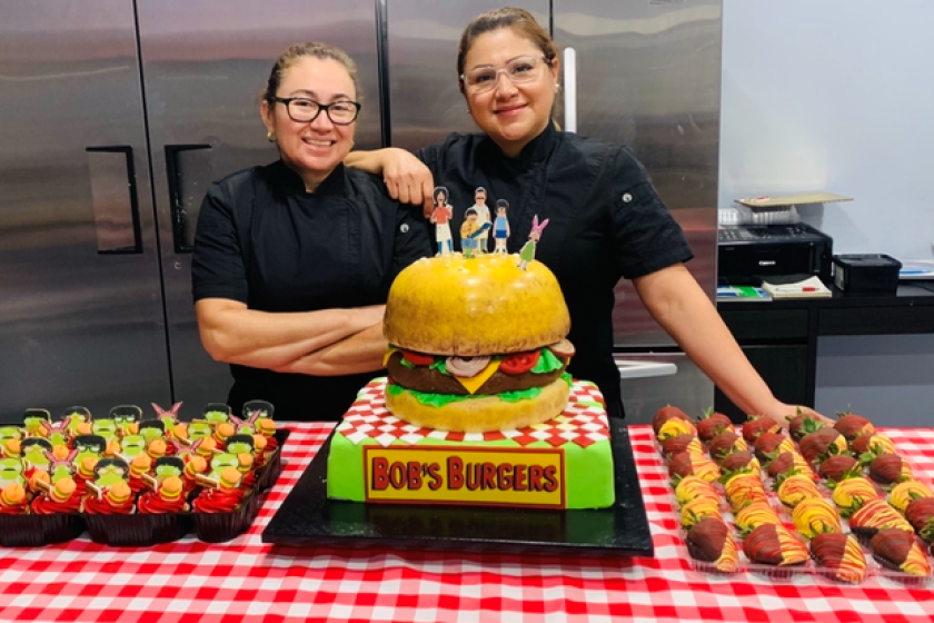 Silvia Navas y Elba Argueta (derecha) aparecen junto a un pastel en forma de hamburguesa.