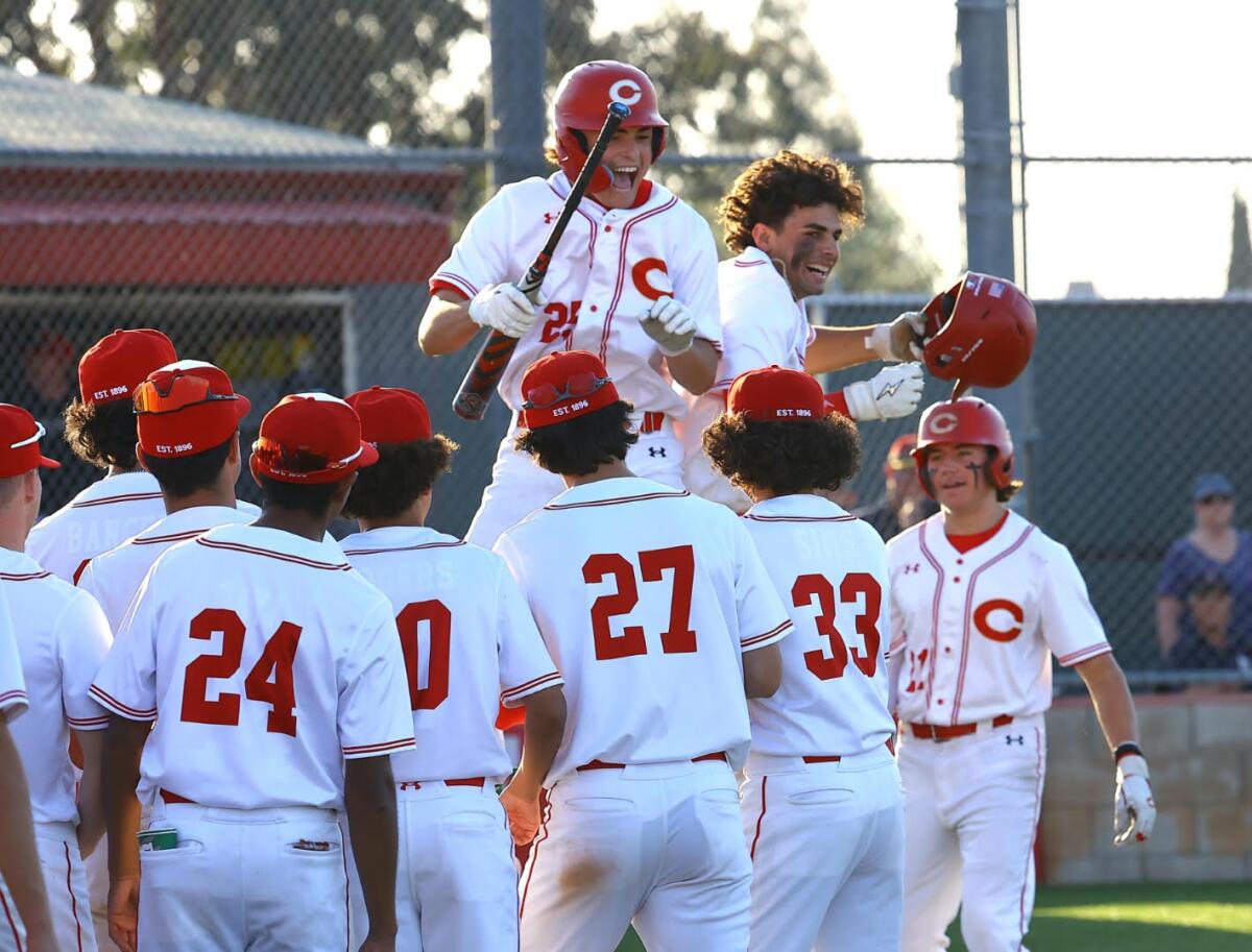 Trey Ebel (right with helmet off) celebrates hitting a sixth-inning home run for Corona with brother Brady (left).