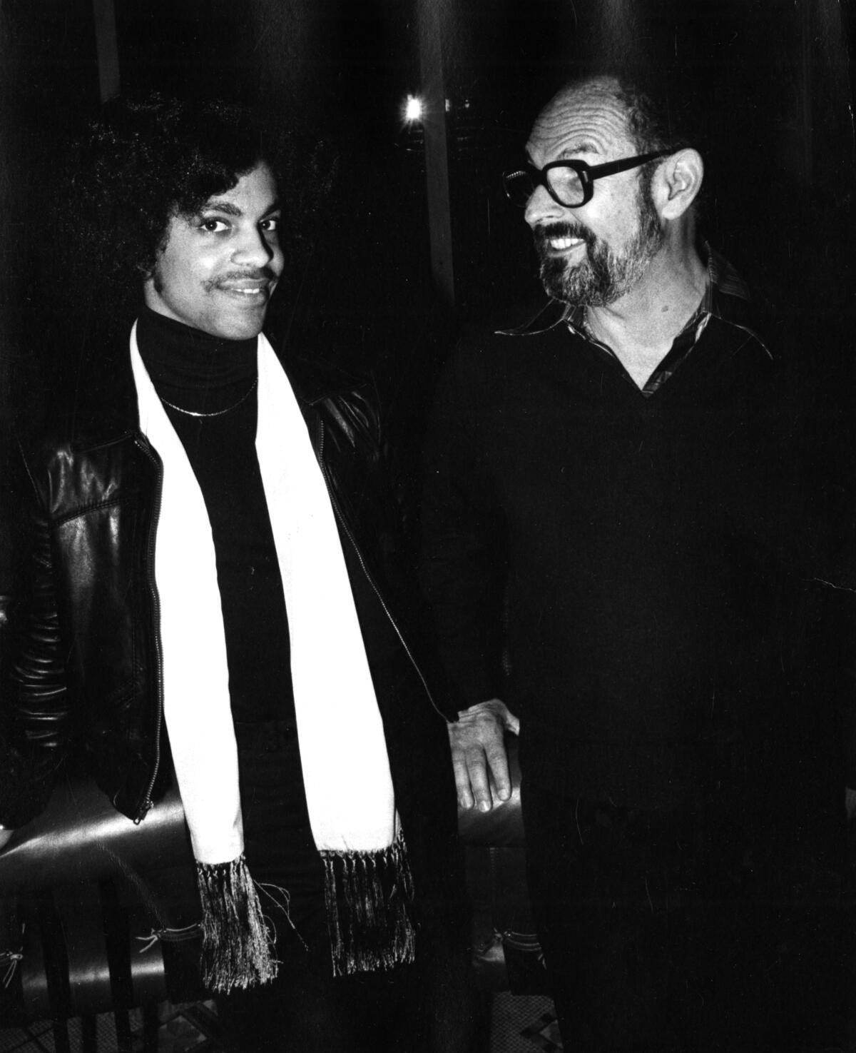 A black-and-white photo of two men, one wearing a long white scarf