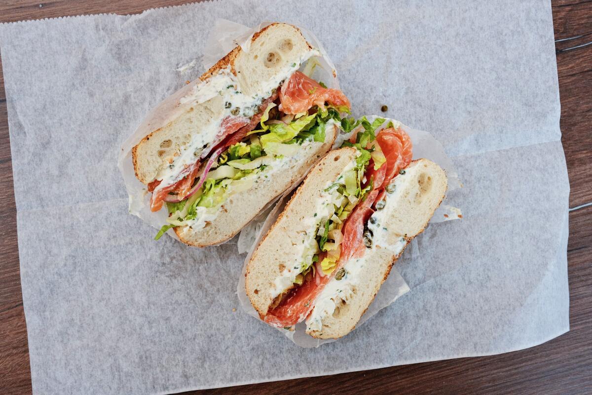 An overhead photo of two halves of a lox and cream cheese bagel sandwich on wax paper at bagel shop Bagel Boss in Burbank.