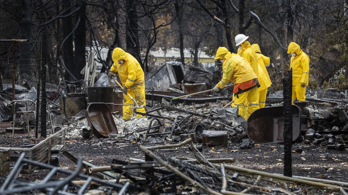 Teams work in the rain Friday as they look for human remains in the ash and debris of a Paradise home.