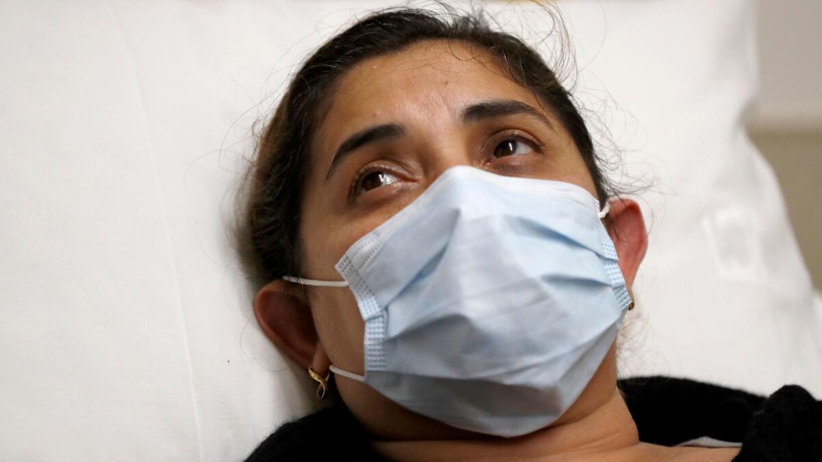 Adriana Gudinoperez, of Garden Grove, a patient with flu symptoms, looks at a nurse after being given ibuprofen in the emergency room at St. Joseph's Hospital in Orange on Friday.