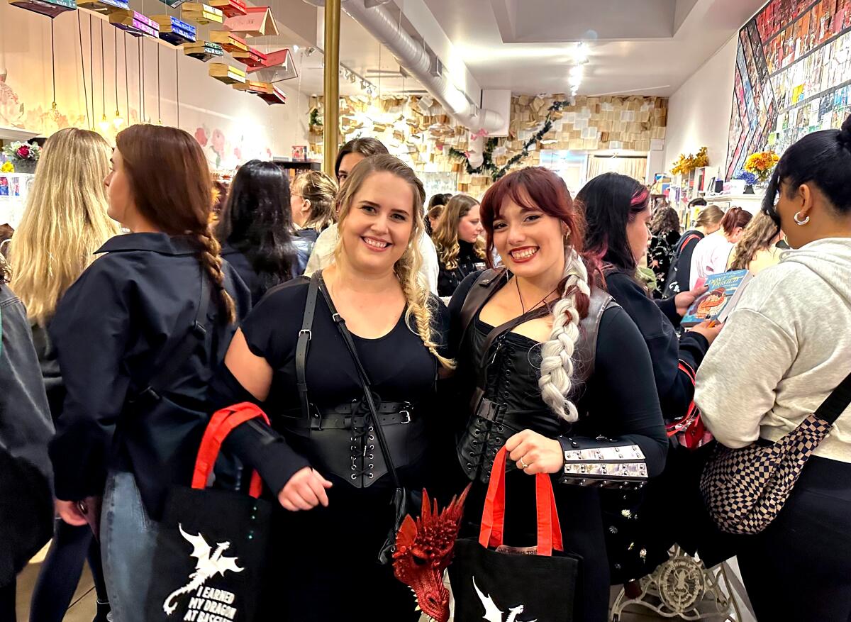 Two women in colorful outfits at a book launch party in a bookstore.