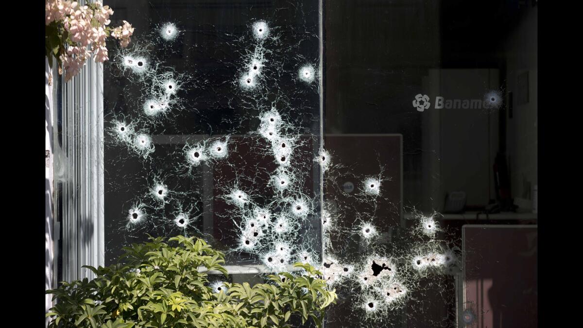 The window of a bank is riddled with bullet holes in the town of Apatzingan in Michoacan state, Mexico on Jan. 11, 2014. Residents from various towns were destroying property to protest the arrival of vigilantes, or members of "self-defense" groups, to their communities.