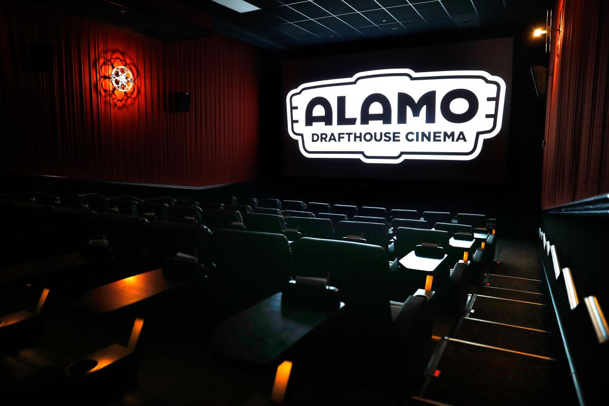 An empty movie theater with the logo for Alamo Drafthouse Cinema glowing on the screen