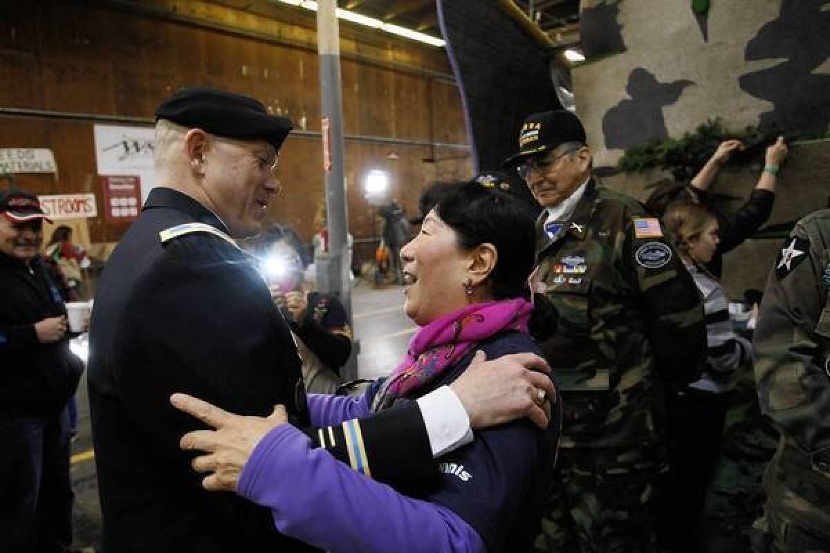 Byoung Baek, center, greets Col. David J. Clark, left, as volunteers decorate the Rose Parade float honoring veterans of the Korean War. In the background is former Army paratrooper Robert Castillo, 82.