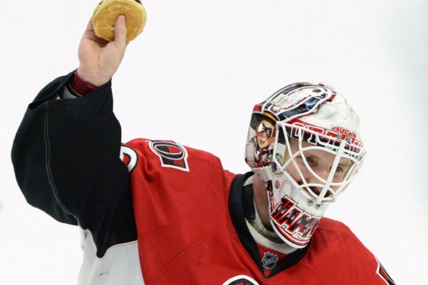 Senators goalie Andrew Hammond, nicknamed 'Hamburglar', holds up a hamburger that was thrown on the ice after a Senators' shootout victory.