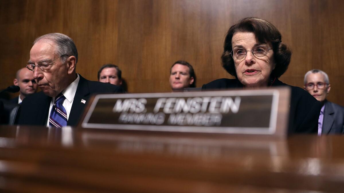 A man and a woman sit at a table with the nameplate Mrs. Feinstein on it.