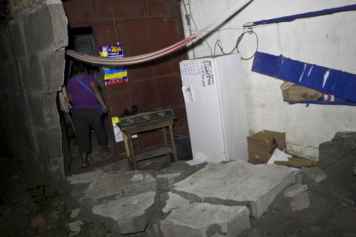 A woman walks inside a home that was damaged by a magnitude 6.1 earthquake in Nagarote, Nicaragua.