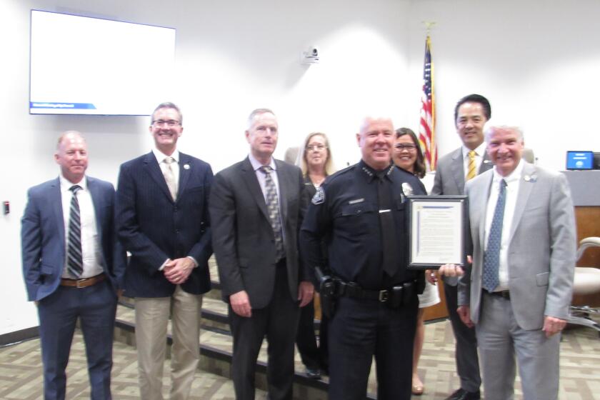 Fountain Valley Police Chief Matthew Sheppard holds up a proclamation recognizing his service to the city.