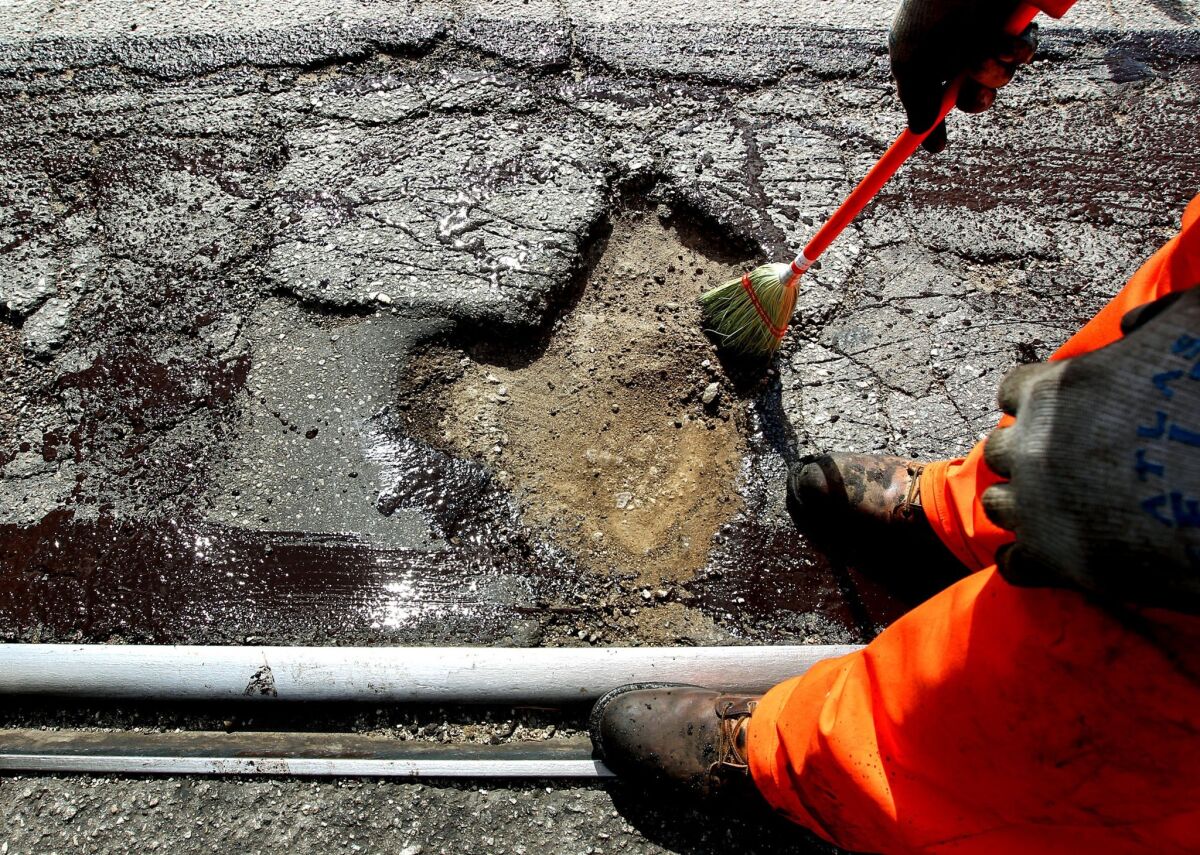 An L.A. Street Services worker prepares to fill a pothole on Alameda Street in June.