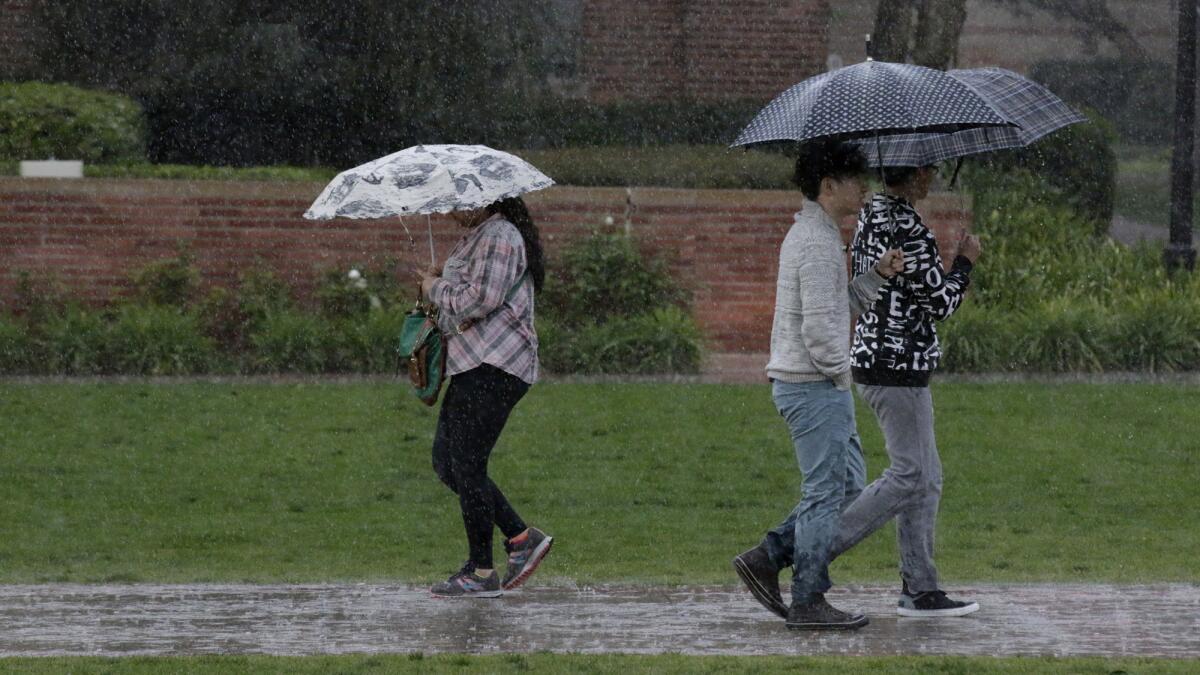 People walk across the UCLA campus in the rain.