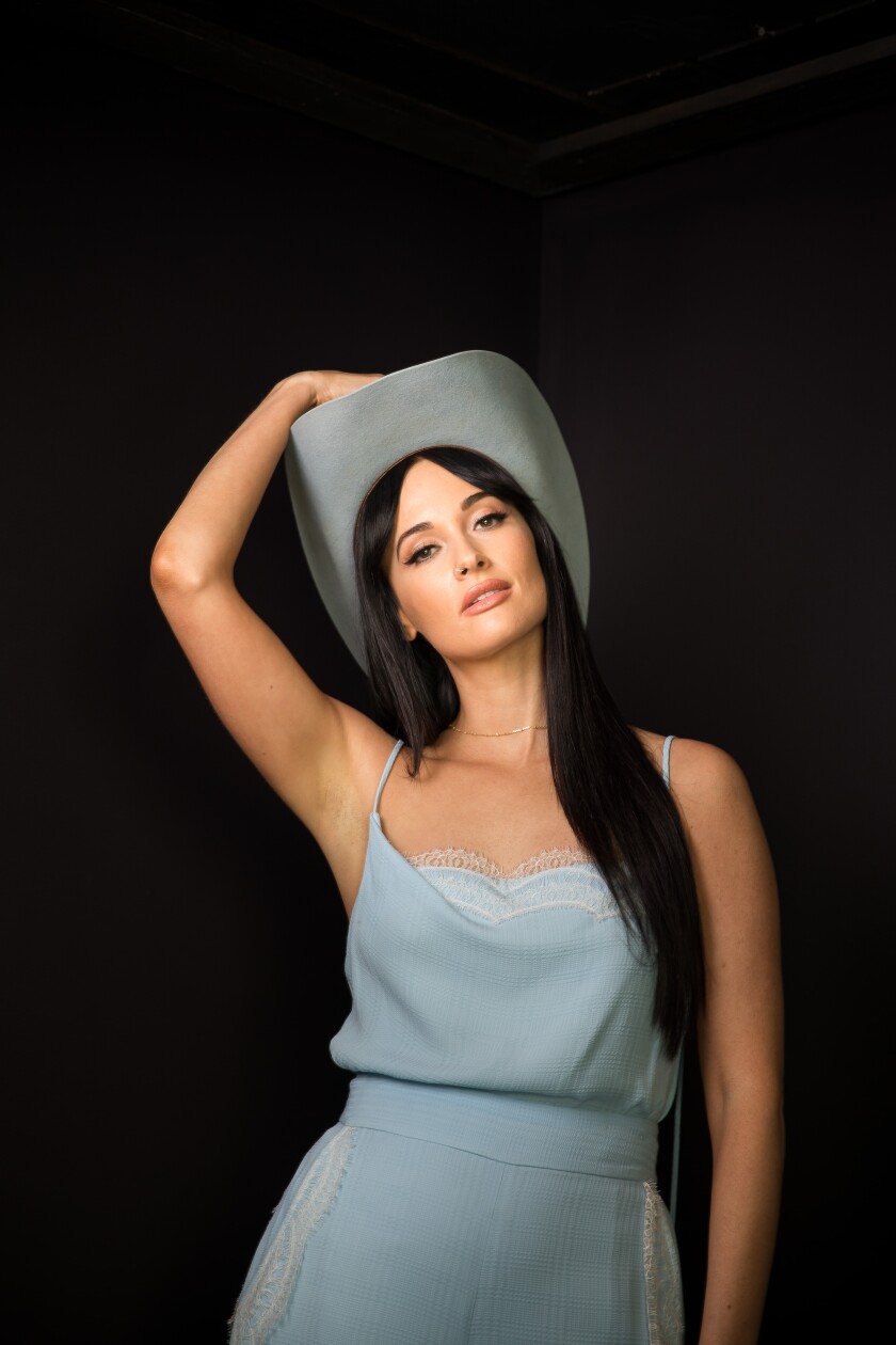 Kacey Musgraves posing in a baby blue dress and cowboy hat