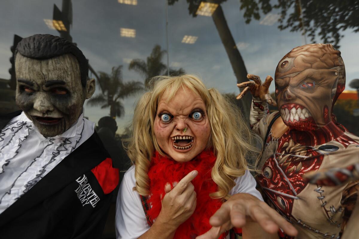 Alan Urban, from left, his brother David, and Nicci Pearce, right, get into the spirit while joining fellow costumed revelers at the annual Halloween Carnaval.