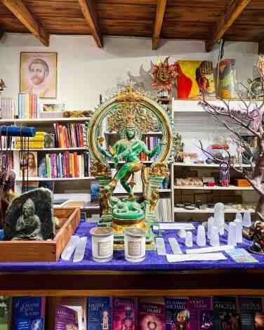 A Shiva statue on a counter, with books on the wall behind, at Spiral Staircase in Topanga.