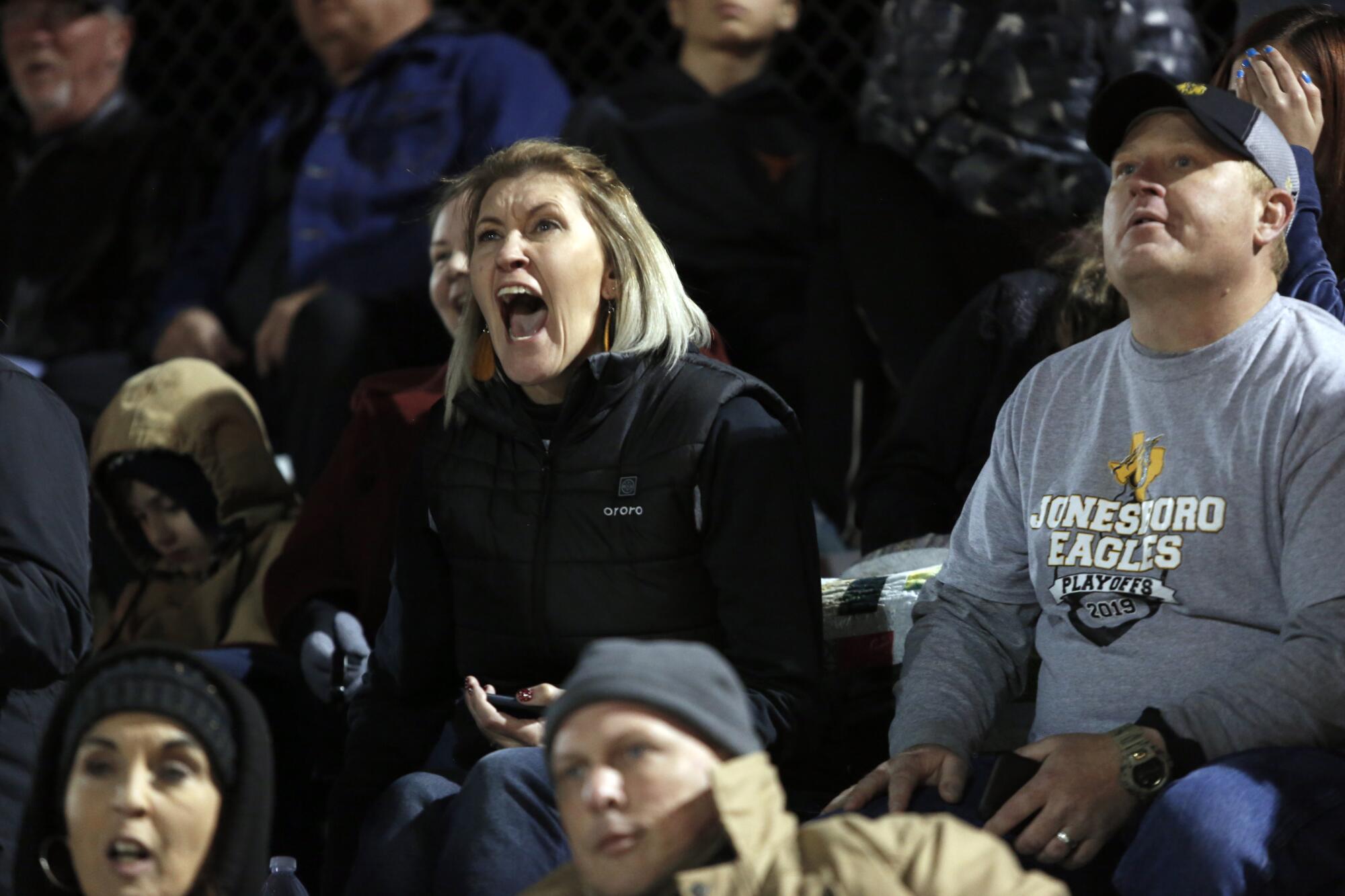 Trinity Sanders roots for her sons, Jonesboro players Keith Sanders (No. 3) and Kaleb Sanders (No. 20), during the semifinals of Texas 6-man 1A Football where Blum and Jonesboro fight for a spot in the state championships in Hico, Texas. Her husband, Adrian Sanders, is on the right. 