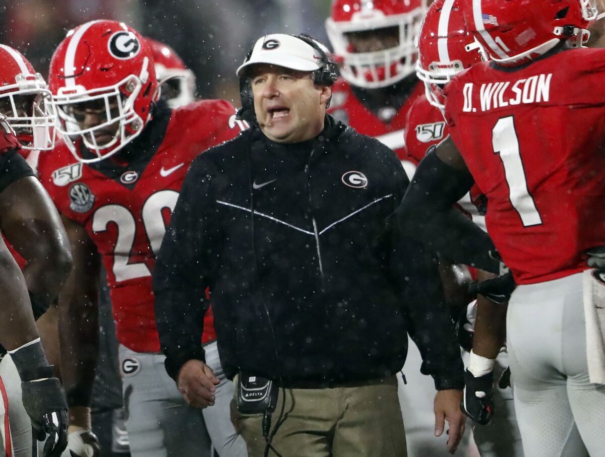 FILE - In this Oct. 19, 2019, file photo, Georgia coach Kirby Smart, center, talks to his players during a timeout in the first half of the team's NCAA college football game against Kentucky in Athens, Ga. There will be much interest in possible changes coming to No. 4 Georgia’s offense with a new quarterback, who is expected to be Wake Forest transfer Jamie Newman, and a new coordinator, Todd Monken. Still, Smart’s Bulldogs may lean on their experienced defense in the pandemic-delayed season. (AP Photo/John Bazemore, File)