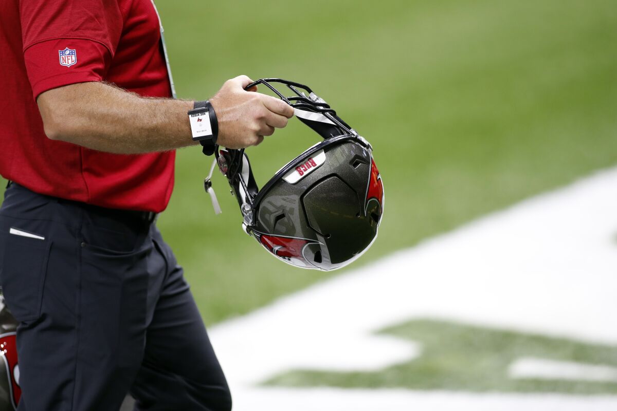 A Tampa Bay Buccaneers employee holds a team helmet while wearing one of the "SafeTags".