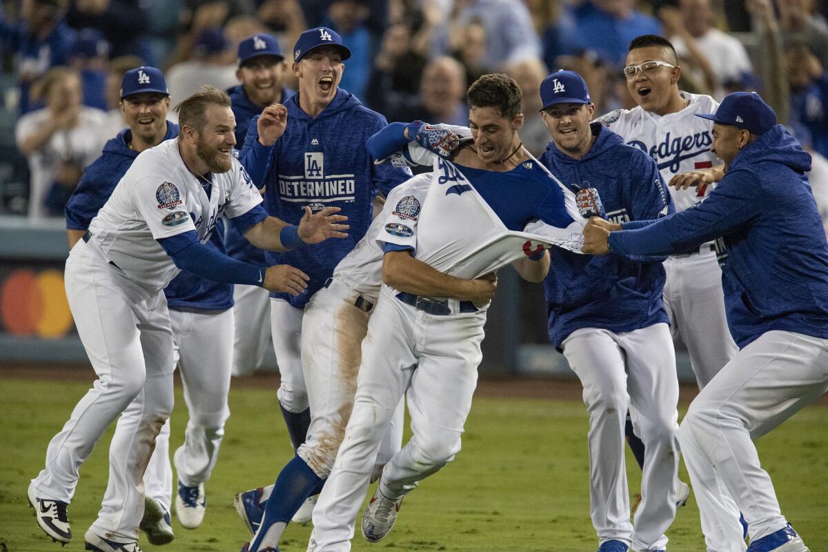 Teammates mob Los Angeles Dodgers center fielder Cody Bellinger after he hit the game winning RBI in the 13th inning during Game 4 of the NLCS at Dodger Stadium.