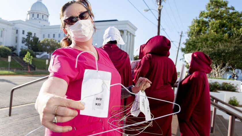 Laura Stiller hands out coat hangers as she talks about illegal abortions during a rally against a near-total ban on abortion outside the Alabama statehouse in Montgomery on Tuesday.