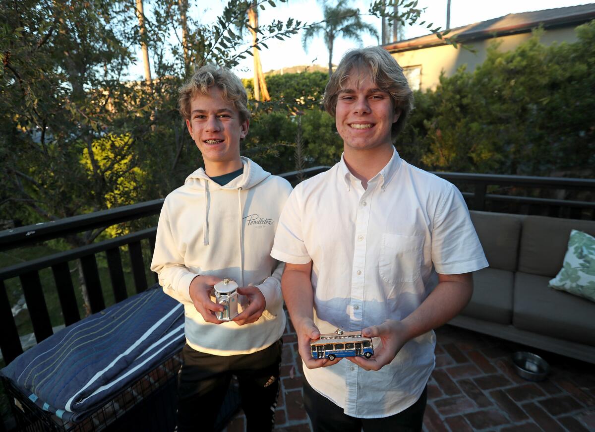 Sawyer and Jackson Collins, from left, hold two ornaments as part of their Iconic Ornaments business in Laguna Beach.