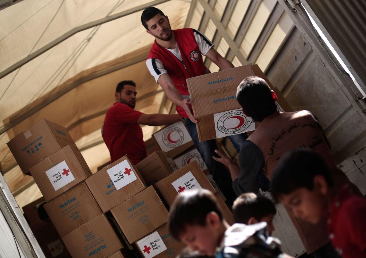 Members of the Syrian Arab Red Crescent deliver aid boxes, some from the German Red Cross, to the besieged rebel bastion of Douma, a flashpoint near the Syrian capital in May 2016.