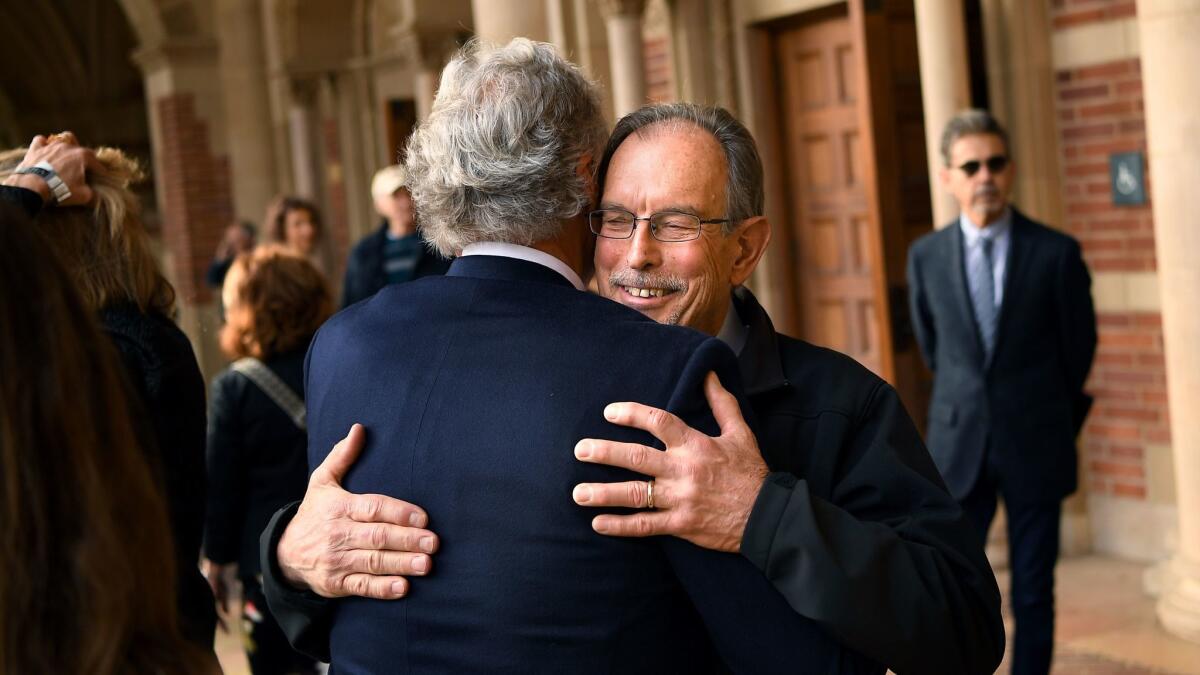Friends Dan Martin, right, and Michael Deiden embrace before a memorial service for activist and politician Tom Hayden at UCLA's Royce Hall on Sunday.