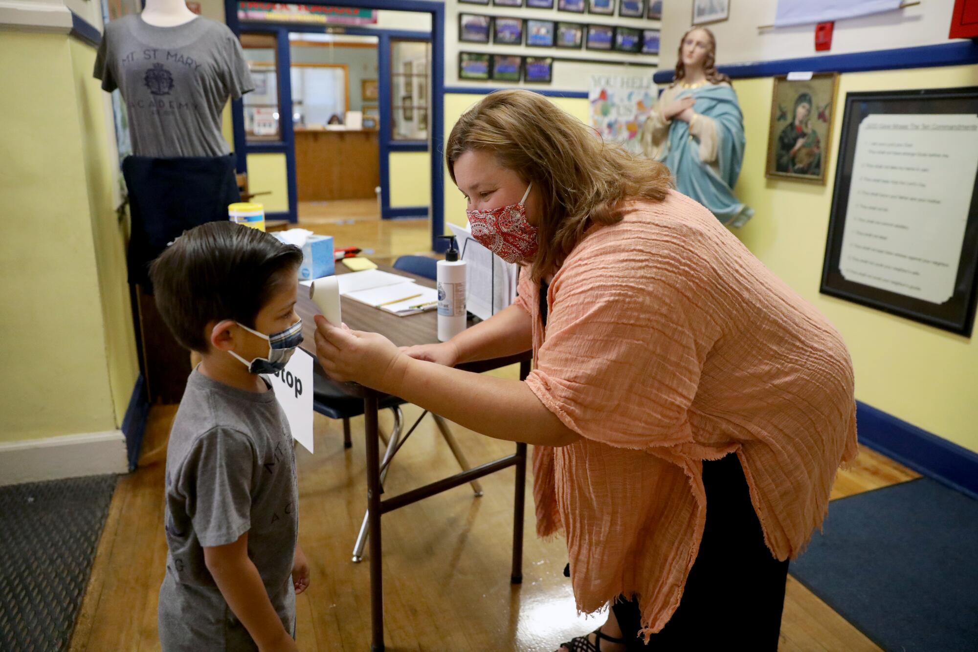 Miles Sirisute, 6, a kindergartner at Mount St. Mary's, has his temperature checked by Principal Edee Wood.