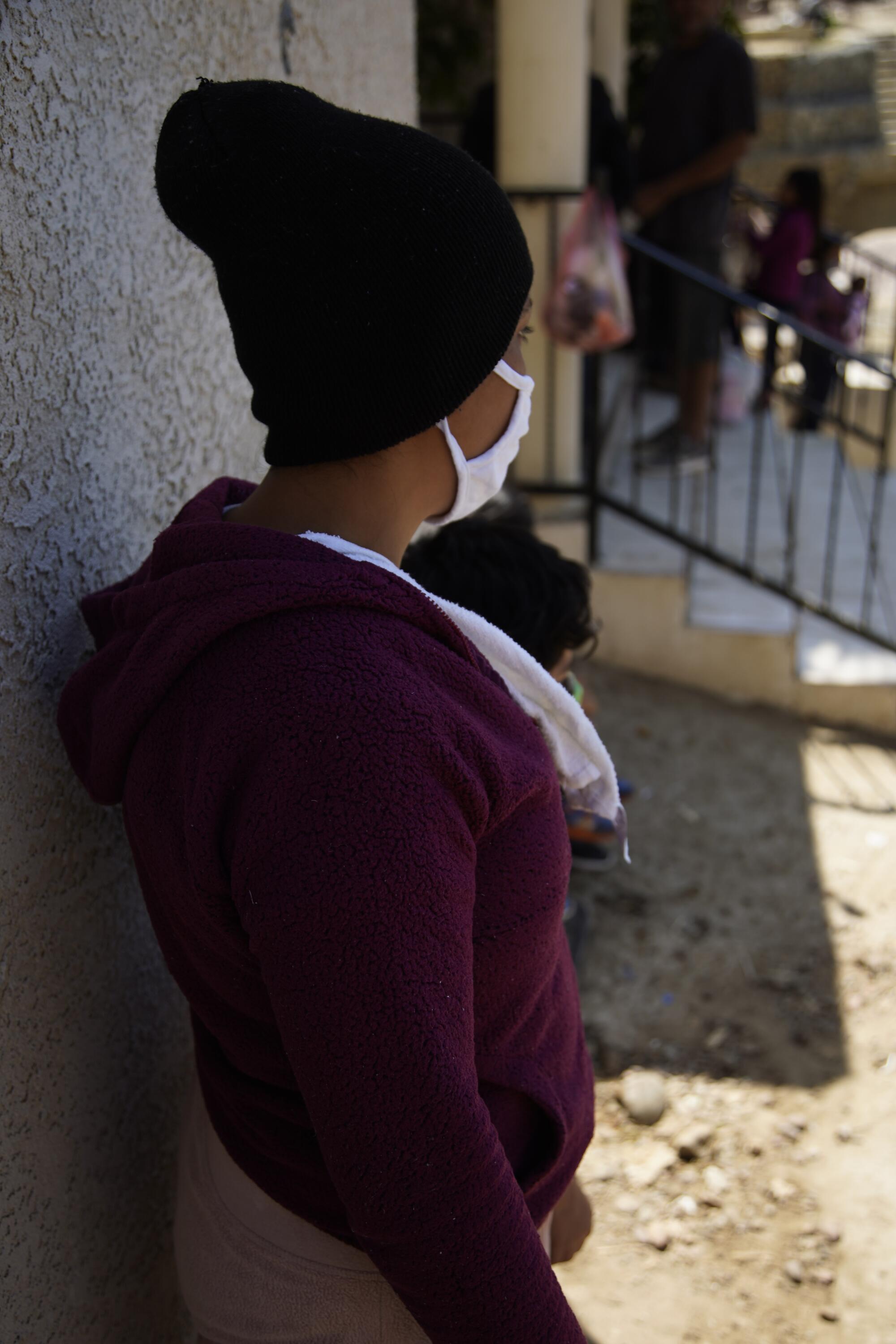 A migrant in Tijuana turns her face away from the camera to avoid being identified