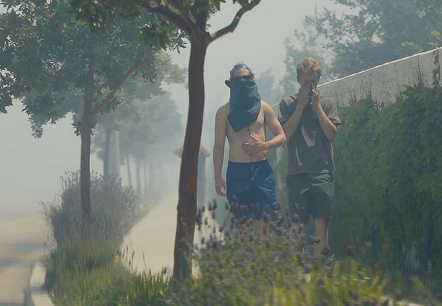 Pedestrians try to protect themselves from the smoky air along Borchard Road in Newbury Park.