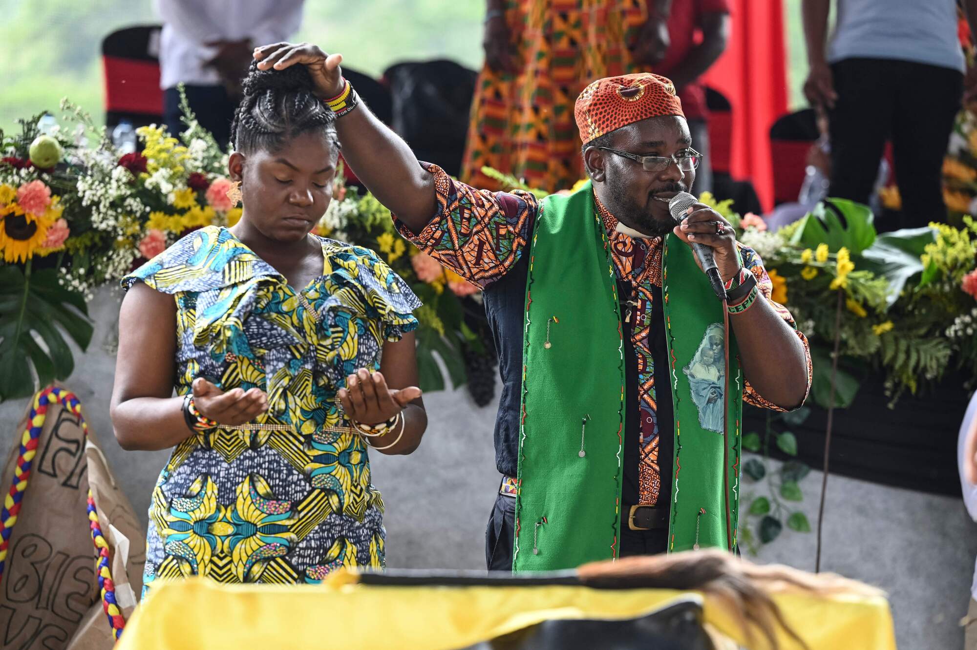 A man and woman in festive clothing surrounded by colorful flowers 