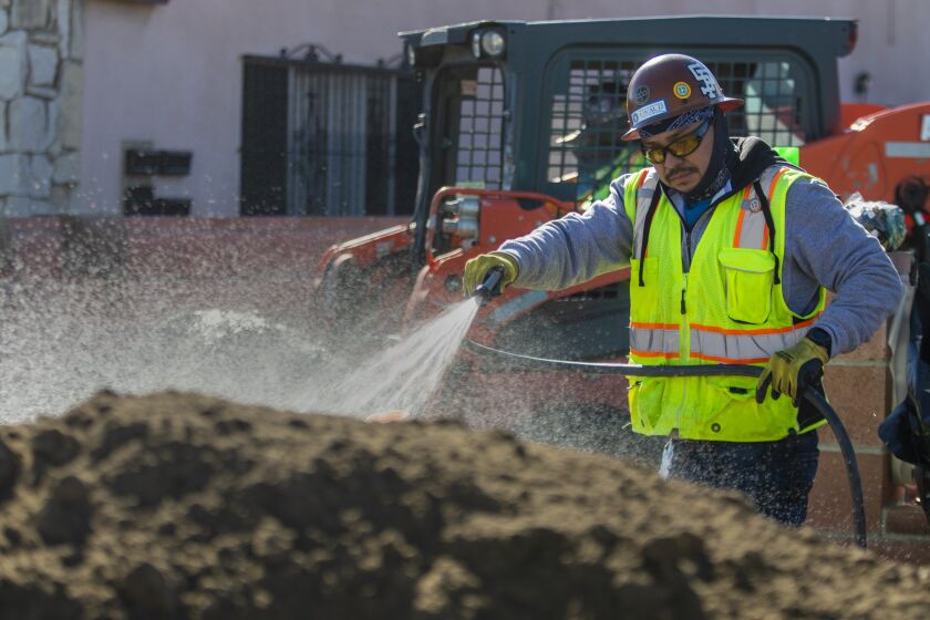 Maywood, CA - November 10: A worker spray water on a pile of contaminated soil before moving it on Thursday, Nov. 10, 2022, in Maywood, CA. Properties have dangerous amounts of lead in their soils after decades of being coated by pollution from a nearby lead-acid car battery smelter (Exide Technologies). The state has cleaned up about 4,000 properties within a 10,000-parcel area that was affected by this pollution. (Francine Orr / Los Angeles Times)