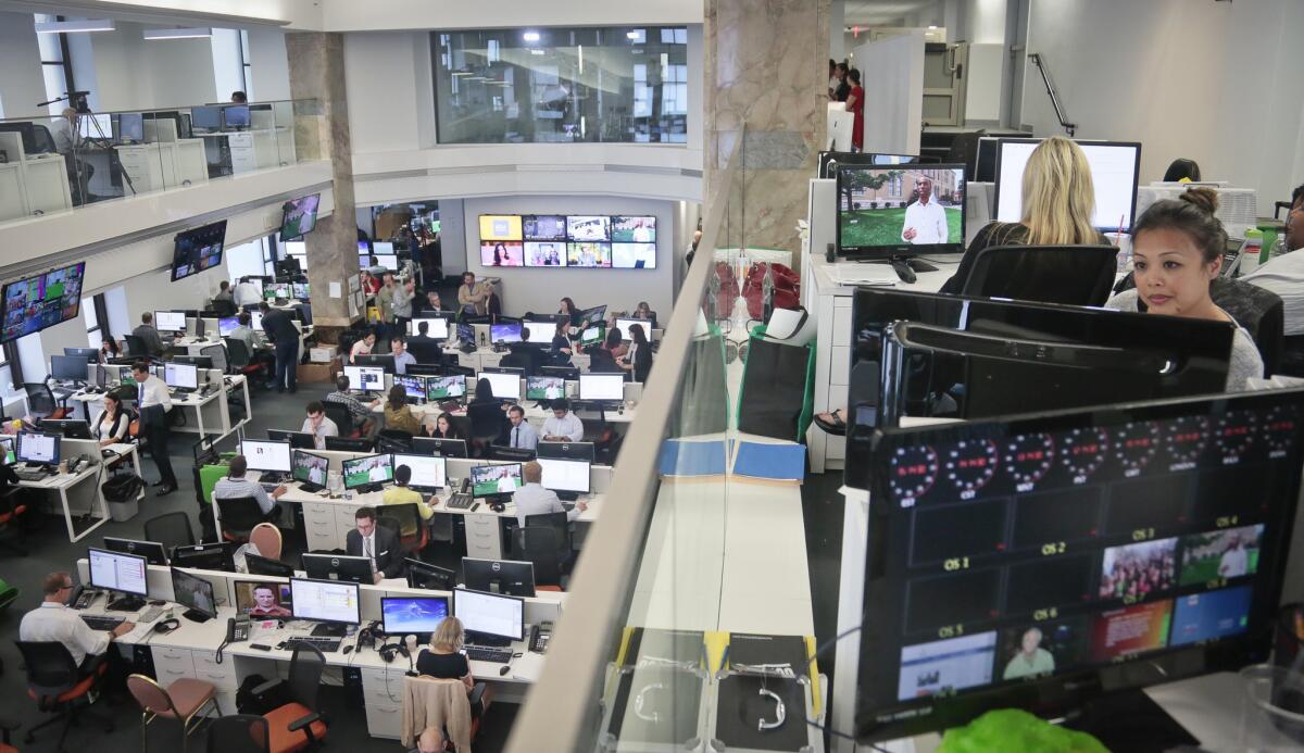 Staffers work in the Al Jazeera America newsroom after the network's first broadcast. The channel will roll out to Time Warner Cable and Bright House Networks customers over the next six months.